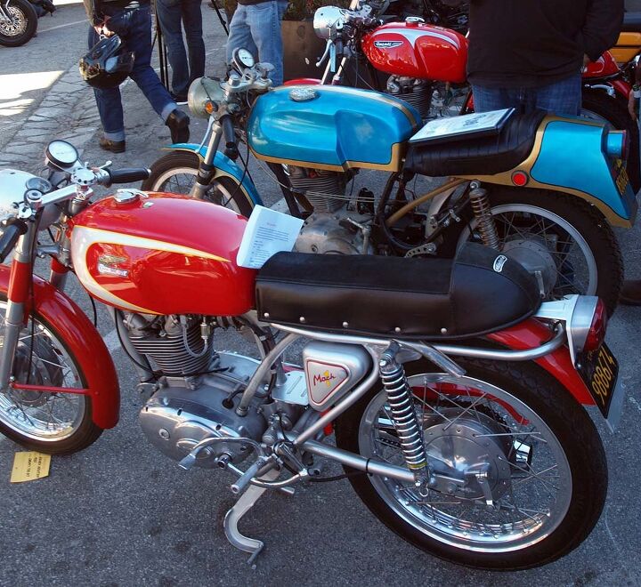 raduno italia dancing with ducs at deus ex machina, A trio of 1960s single cylinder Ducs included in foreground a very red 1965 Mach I also brought by Wendy Newton while the blue machine is Michelle van Vilet s 1969 350 Desmo Scrambler In the background Maurizio Sanges 1967 250 Desmo