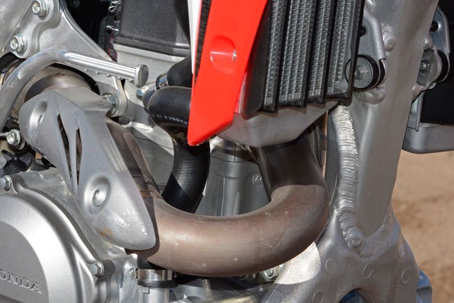 2015 honda crf450r first ride review, The CRF450R s Unicam cylinder head is new for 2015 with a revised exhaust port that exits to the right of the head centerline This eliminates the need for the CRF s exhaust header to wrap around the frame downtube
