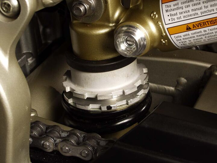 adjusting motorcycle suspension, Here s a monoshock and its locking ring spring preload adjuster The shiny bit in the upper middle of the photo is the compression damping adjusting screw Note the S soft and H hard markings Photo by Evans Brasfield