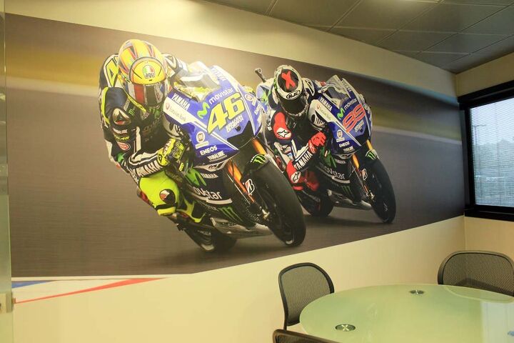 inside yamaha s motogp race shop, Wall art Jarvis tells us that Rossi is super analytical with his bike s setup William Favero Communications Manager of Yamaha Motor Racing says VR46 would spend all day in the garage with his engineers and mechanics if he could Jarvis believes Lorenzo has been less analytical in the past but is delving deeper into that aspect to make sure he is doing everything he can to remain competitive Lorenzo s skills are so high according to Favero that he could ride a washing machine fast