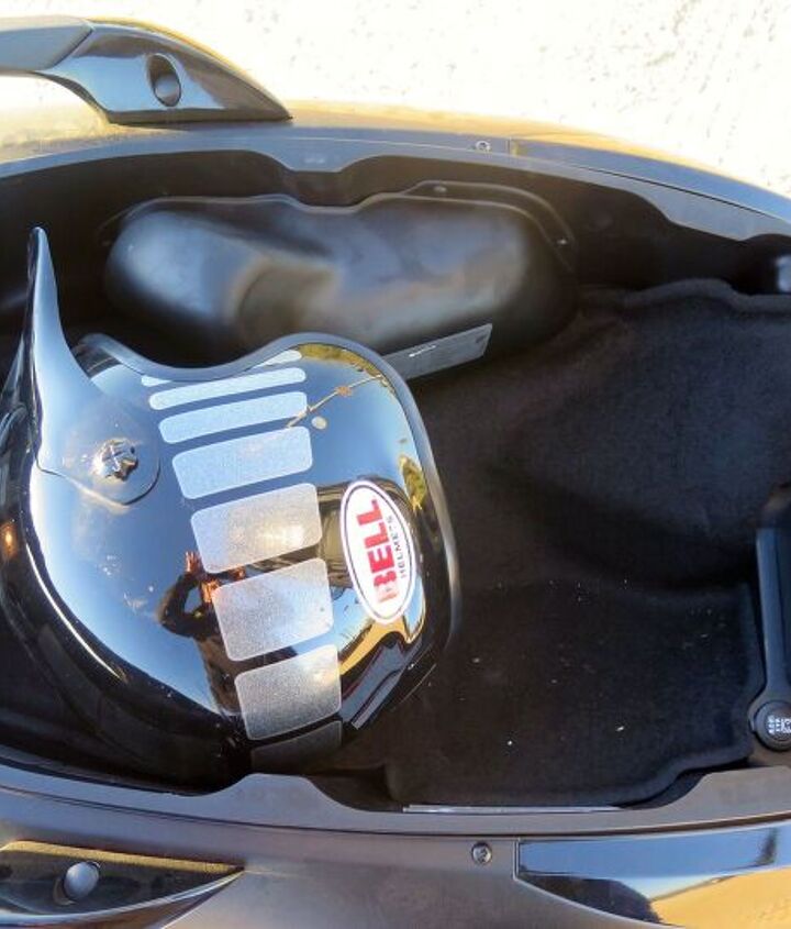 2016 piaggio mp3 500ie review, You can squeeze one full face and one open facer under the seat where there s a light a 12V outlet 180 watts and a nice hydraulic prop to hold the seat up The weird bulge at the top of the photo covers the emissions stuff needed for CARB compliance