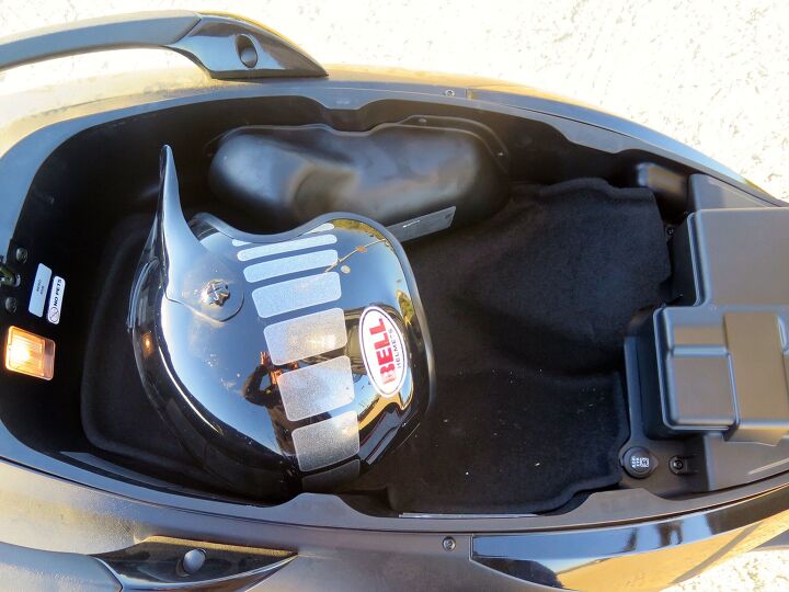 2016 piaggio mp3 500ie review, You can squeeze one full face and one open facer under the seat where there s a light a 12V outlet 180 watts and a nice hydraulic prop to hold the seat up The weird bulge at the top of the photo covers the emissions stuff needed for CARB compliance