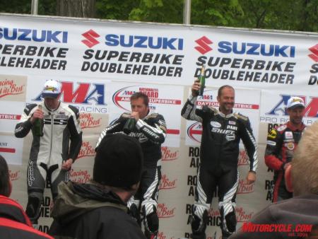 mo goes ama roadracing part 2, Paul James leader of our James Gang Hoban Brothers Racing team holds the champagne bottle high after taking the GT1 class win with teammate Jeff Johnson in mid swig