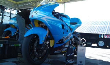 2012 fim e power ttxgp laguna seca race report, Barnes race winning motorcycle poses with the winner s trophy Instead of generators both Team Barracuda Lightning entries used solar panels to charge their machines as seen in the background
