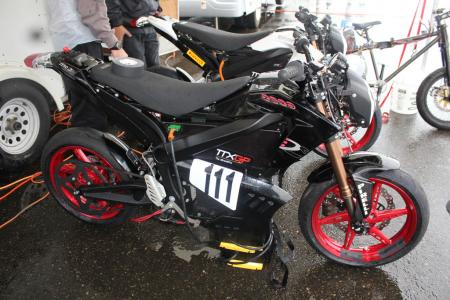 racing electric motorcycles video, What do you get when you take a box stock Zero S and slap numbers on it An E Superstock racer eligible for TTXGP competition Note the yellow boxes on the ground Those are the battery charging units normally mounted on the bike They