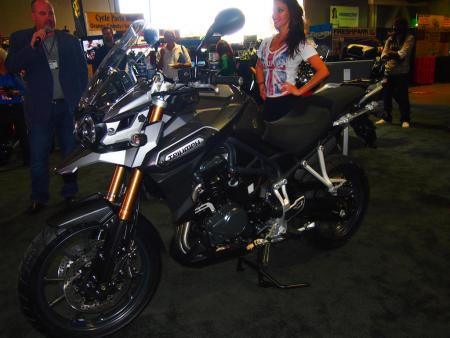 2011 progressive international motorcycle show at long beach video, Triumph North America CEO Greg Heichelbech holding microphone introduced the new Tiger Explorer to the assembled press in commemoration of Triumph s 110th birthday The bike you see here is currently one of two in existence in the U S