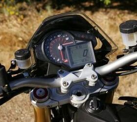 2011 aprilia dorsoduro 1200 review video motorcycle com, The tidy gauge cluster actually reveals a lot A large analog tach dominates but the digital display has a speedo clock odometer tripmeter just one engine temp ride mode and gear position indicator
