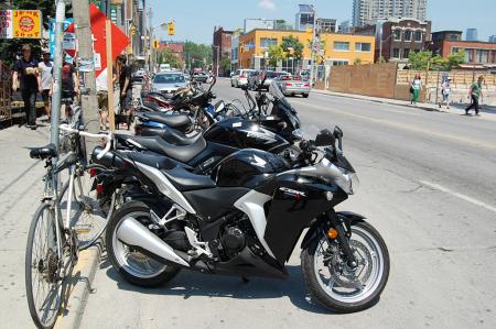 motorcycle beginner year 2 motorcycle ownership, A Honda CBR250R sits in a row of parked motorcycles across from the Motorcycle com Toronto office The little CBR did very well for Honda Canada last year and I usually see at least two or three of them on the street each day
