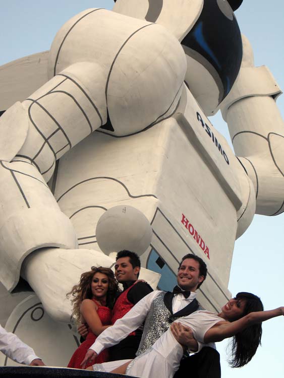 Dancers perform in front of a giant replica of Honda's ASIMO robot to practice for the Rose Parade. Or they're really happy to have something to protect them from Godzilla.