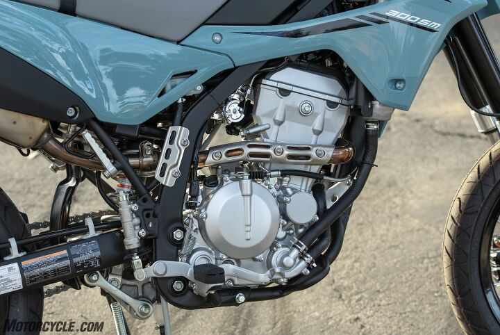 news-720-1 Simple and efficient, the 292cc Single is an admirable performer. Seen here in the SM, the standard KLX has a cover over the throttle cable cam that opens and closes the butterfly as you twist your wrist. Note also the rubber pad on the footpeg. The standard KLX doesn't have that.